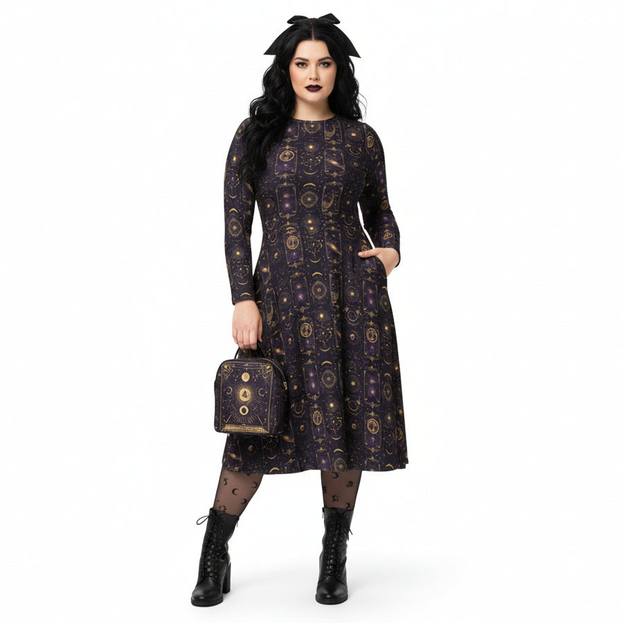 Woman wearing a dark celestial patterned dress holding a matching handbag on a white background