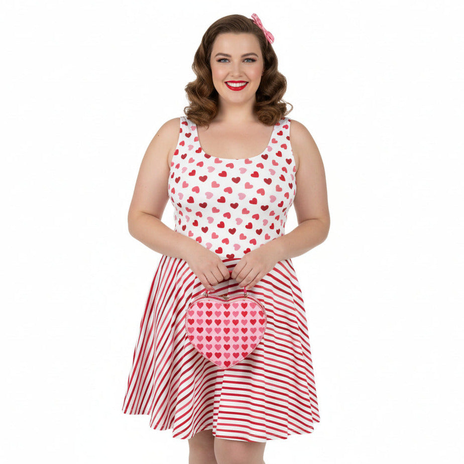 Woman wearing a red and white polka dot dress with a matching handbag on a white background