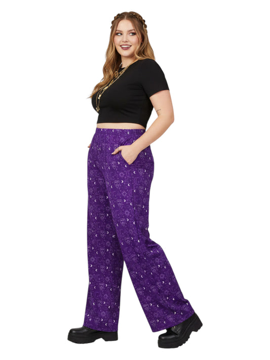 Woman wearing purple Whimsigoth wide leg lounge pants with celestial moon and sun print.
