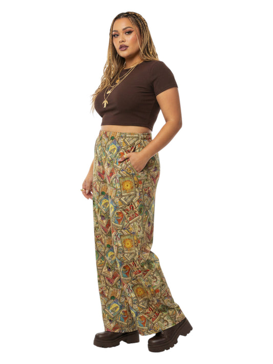 Woman wearing Whimsigoth wide leg lounge pants with vintage tarot card print and practical side pockets.