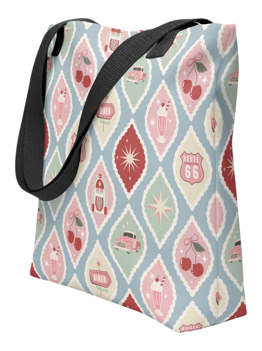 1950s diner retro tote bag with pastel pinup pattern featuring cherries, milkshakes, and jukeboxes on a light blue background with black straps.