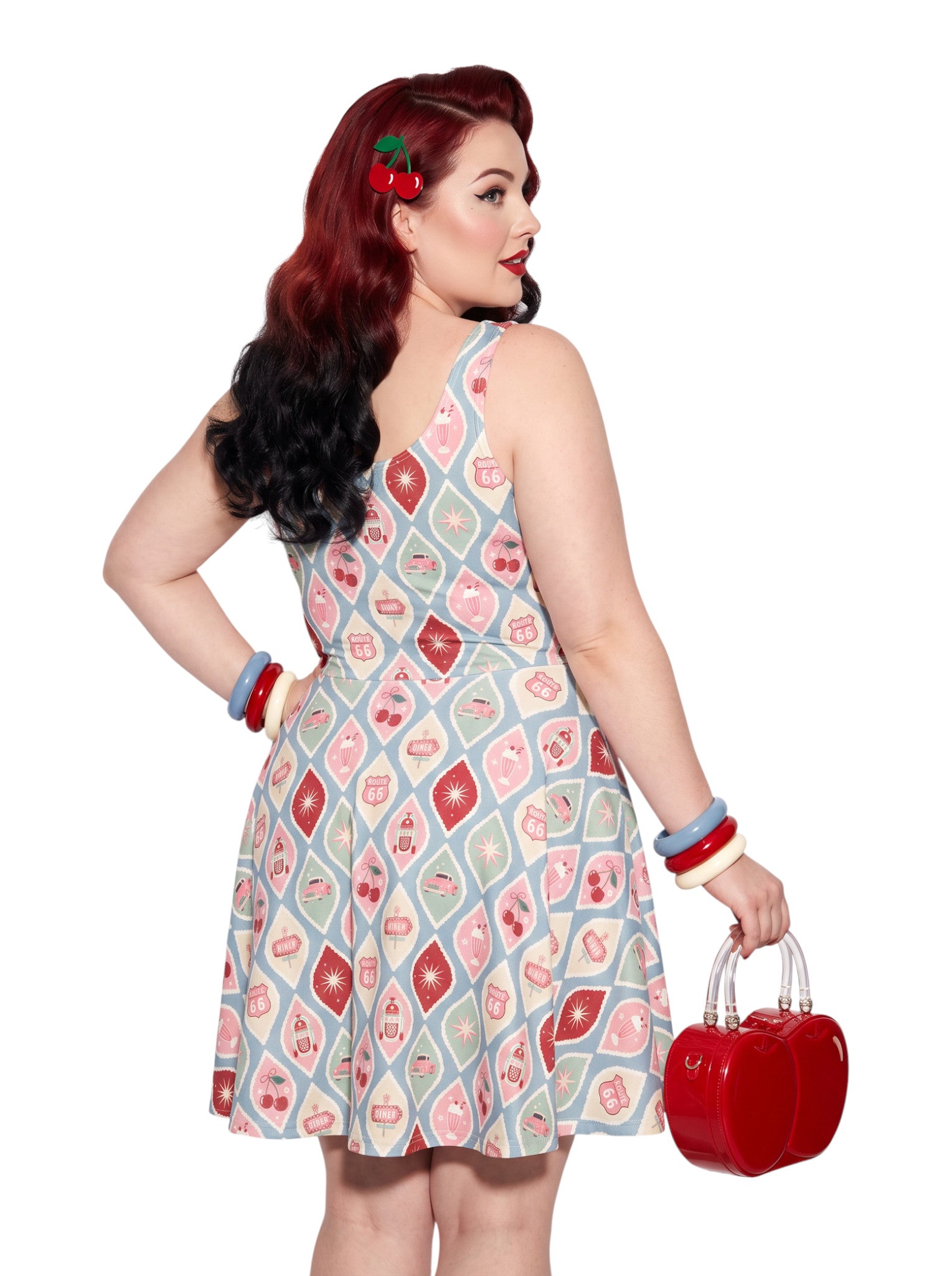 Plus size pinup woman wearing a 1950s style cherry diner milkshake pattern swing dress made of high stretch fabric