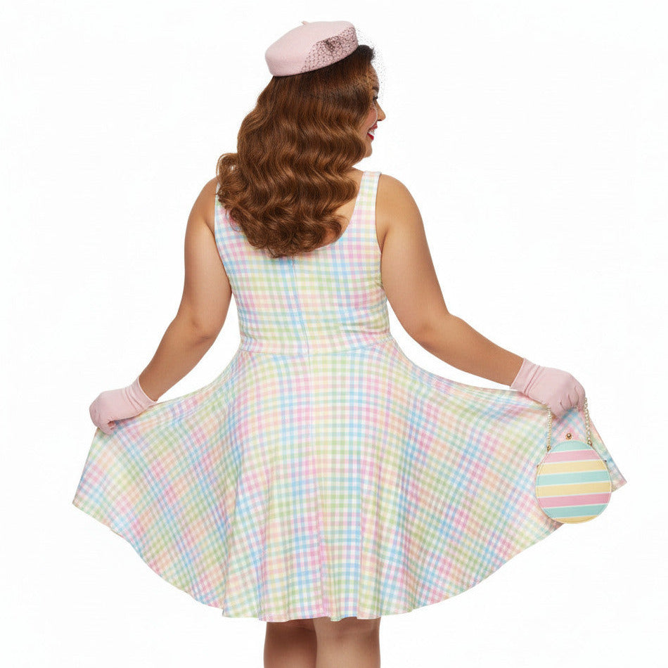Plus size woman wearing a pastel rainbow gingham 1950s vintage-inspired swing dress with a pink pillbox hat and pearl necklace.