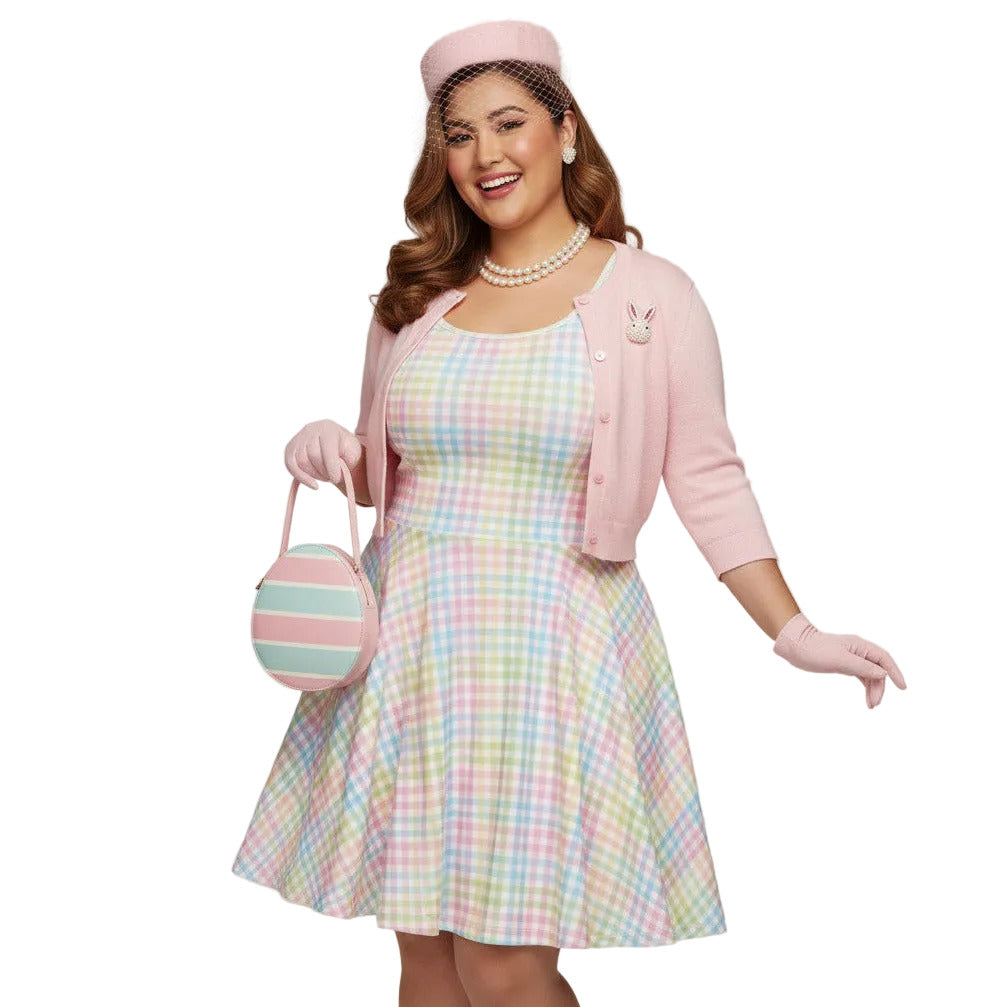 Plus size woman wearing a pastel rainbow gingham 1950s vintage-inspired swing dress with a pink pillbox hat and pearl necklace.