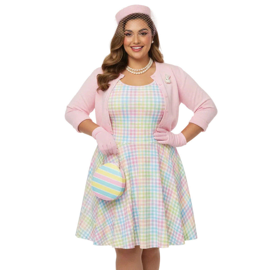 Plus size woman wearing a pastel rainbow gingham 1950s vintage-inspired swing dress with a pink pillbox hat and pearl necklace.
