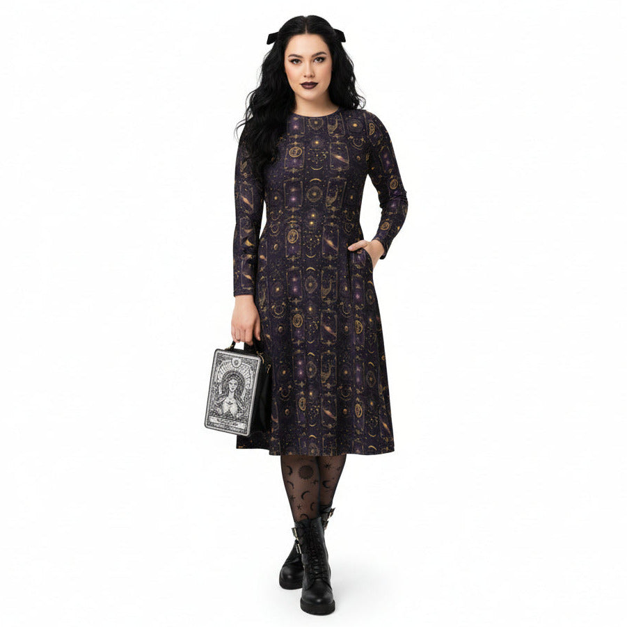 Woman wearing a black dress with a celestial pattern, holding a small bag on a white background