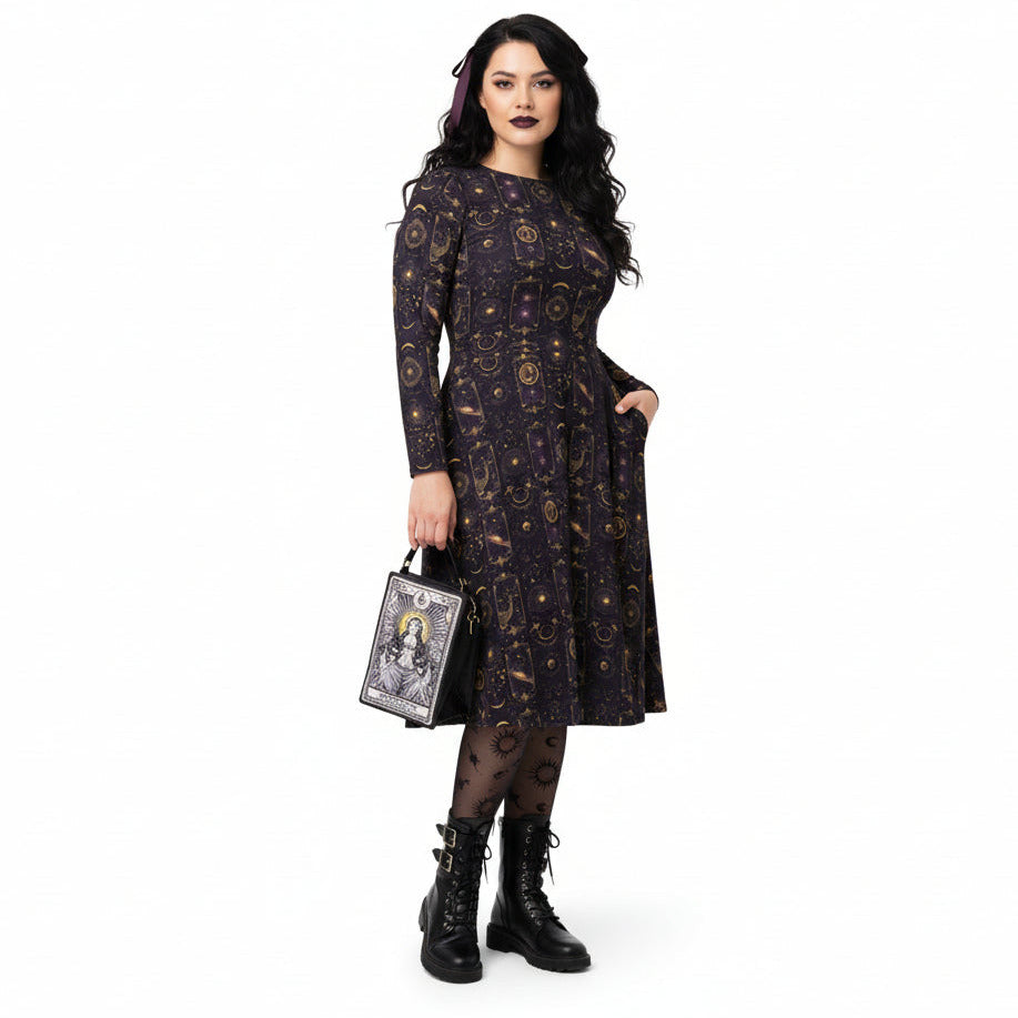 Woman wearing a dark dress with celestial pattern, holding a matching handbag on a white background