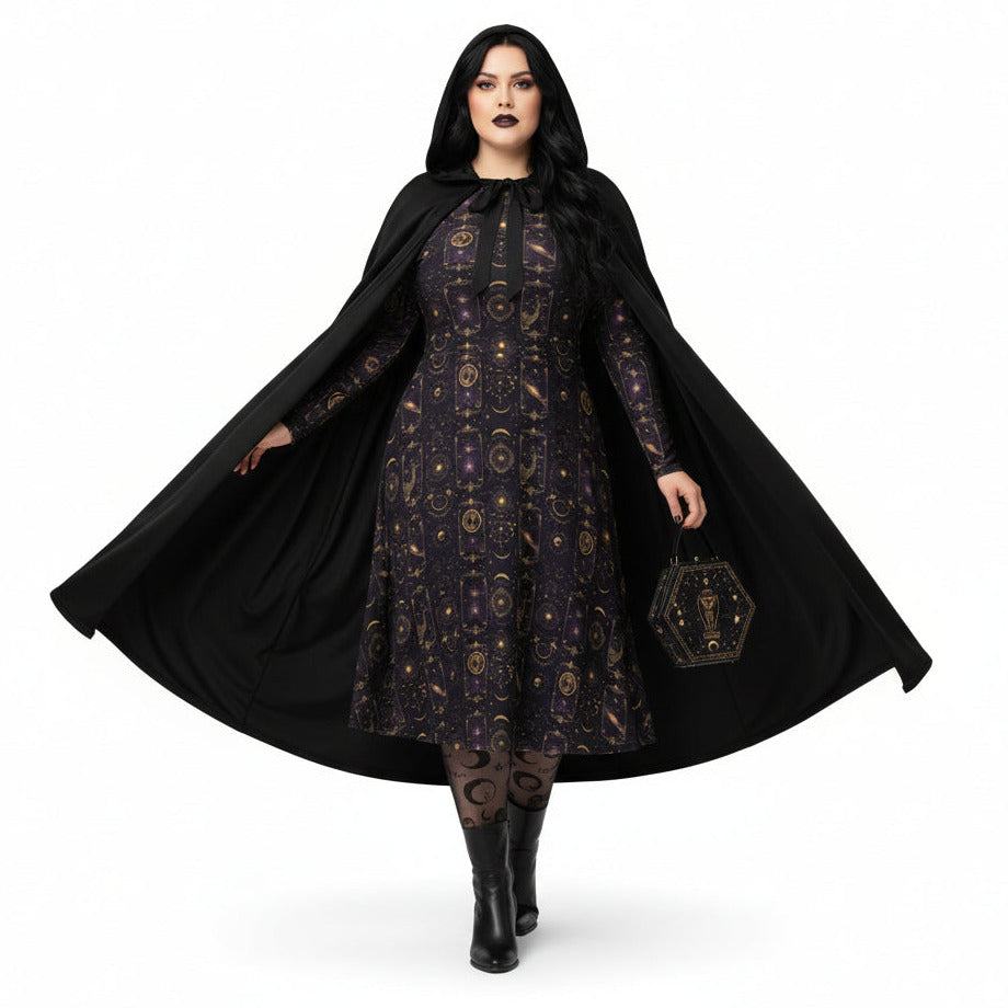 Woman wearing a black dress with gold patterns and a long black cape on a white background