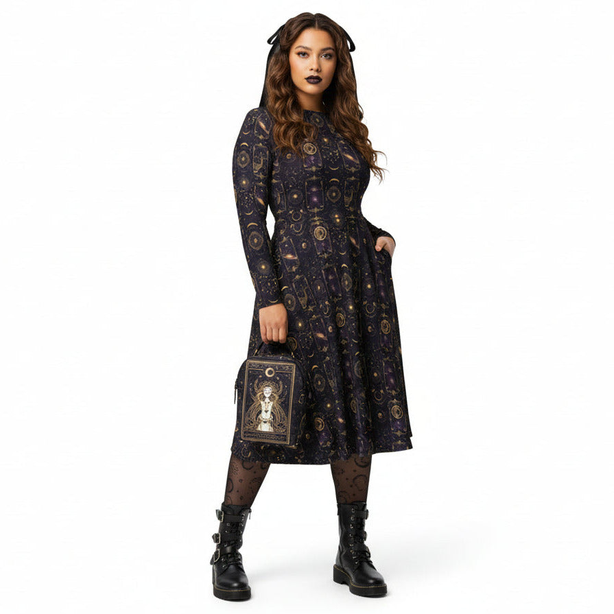Woman wearing a black celestial patterned dress holding a tarot card bag on a white background
