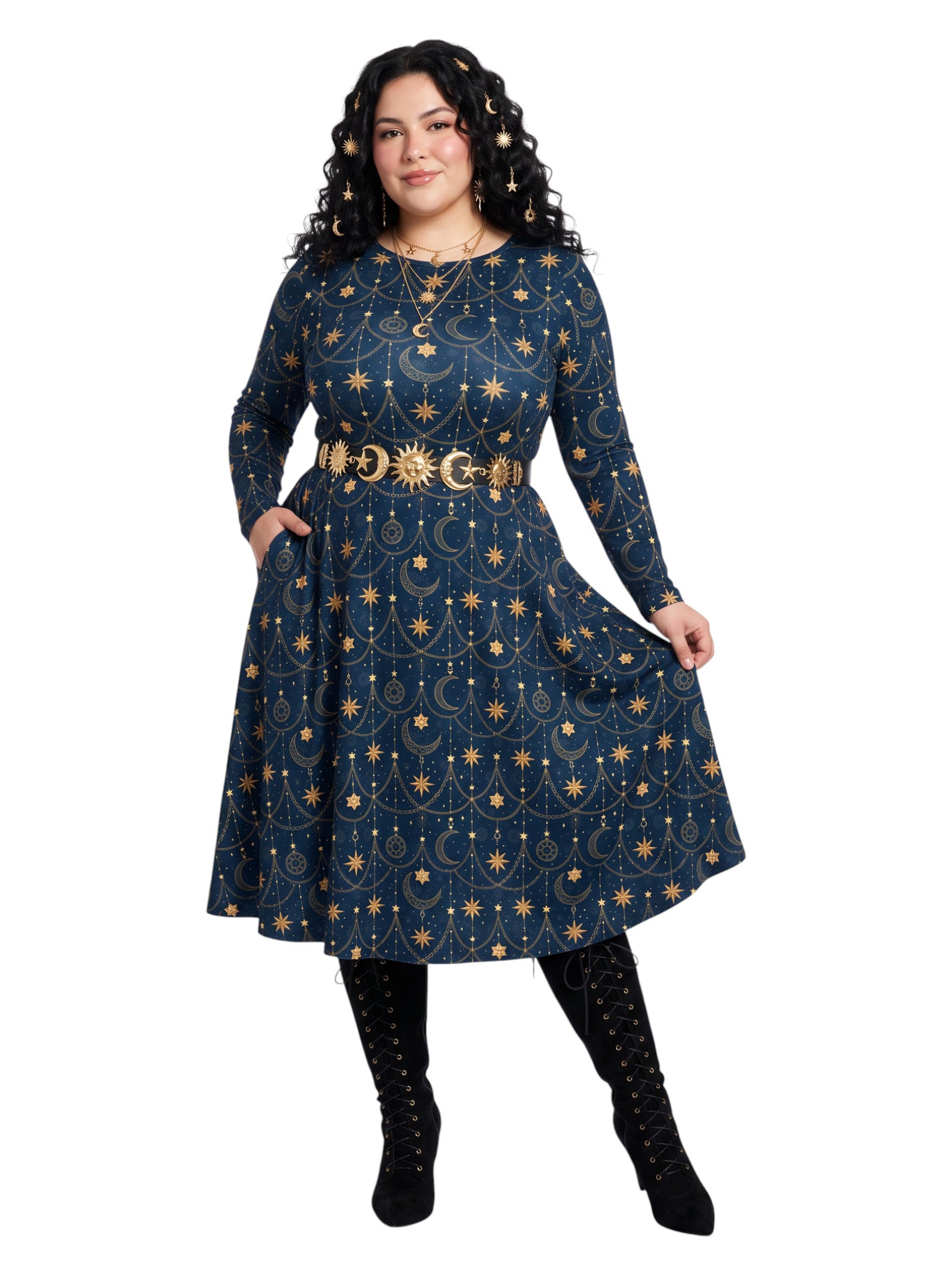 A woman modeling a long-sleeve navy blue midi dress with a gold celestial print of stars, moons, and suns, styled with a matching gold belt and black lace-up boots against a white background.