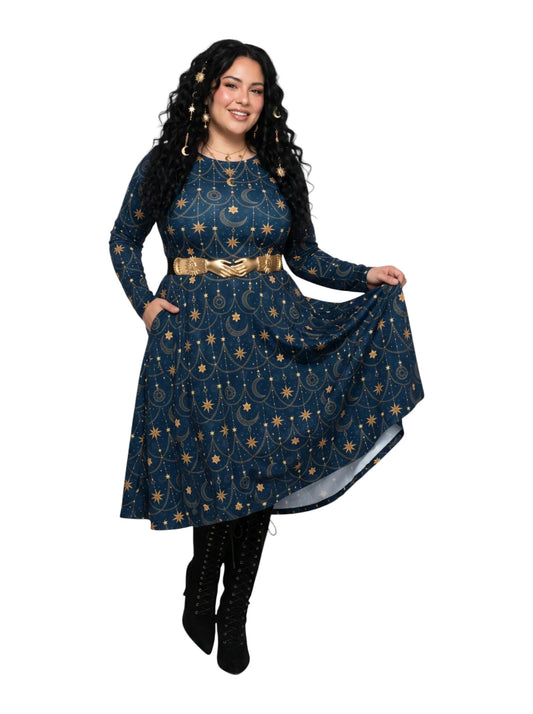 A woman modeling a long-sleeve dark blue dress with a gold celestial print of stars, moons, and suns, accessorized with a wide gold belt, black lace-up boots, and gold statement earrings against a plain white background.