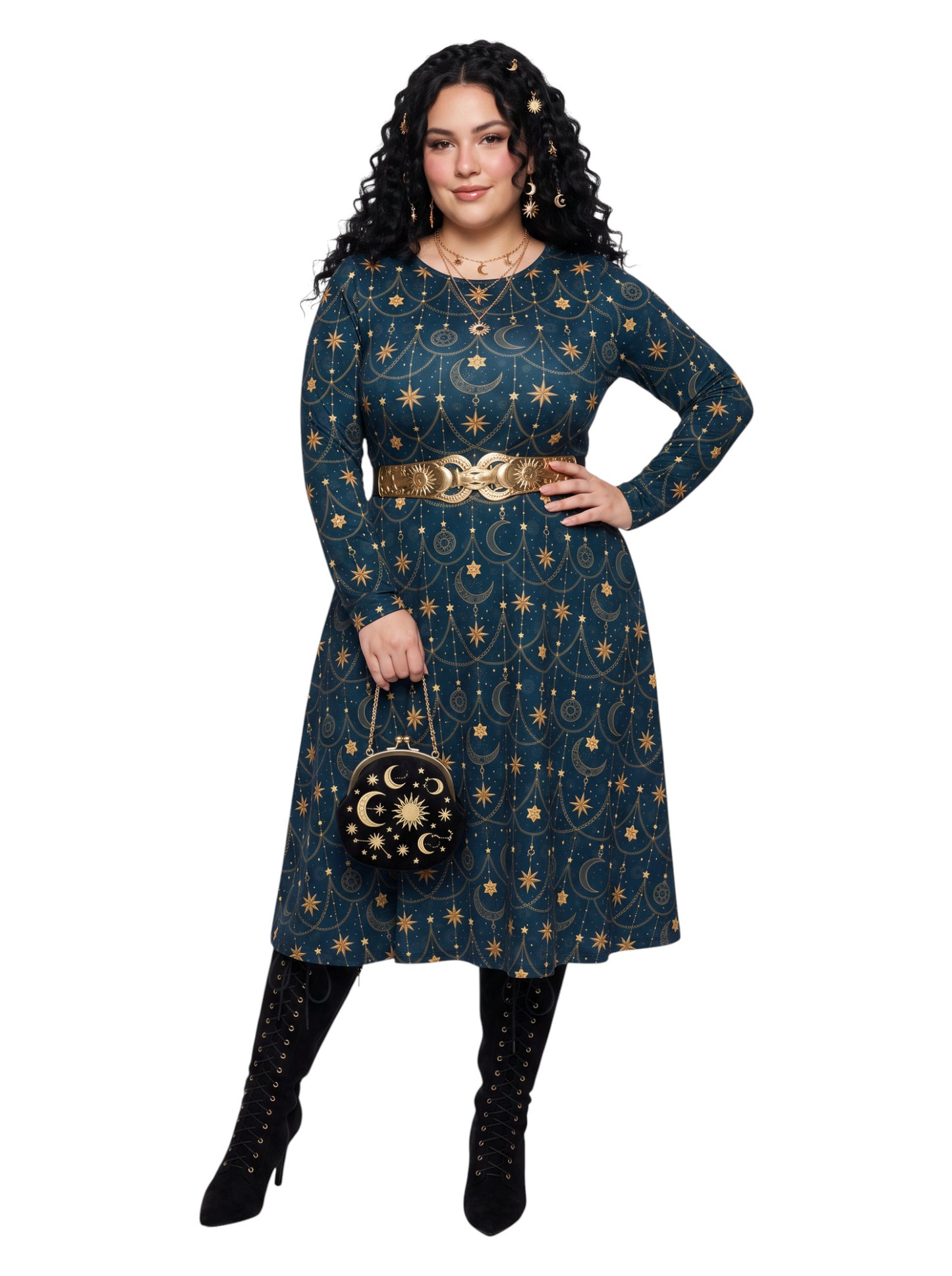 A woman modeling a long-sleeve A-line dress in dark teal with a gold celestial print of stars, moons, and constellations. She is wearing a wide gold chain belt, black lace-up knee-high boots, and holding a small black and gold moon-patterned handbag against a solid white background.