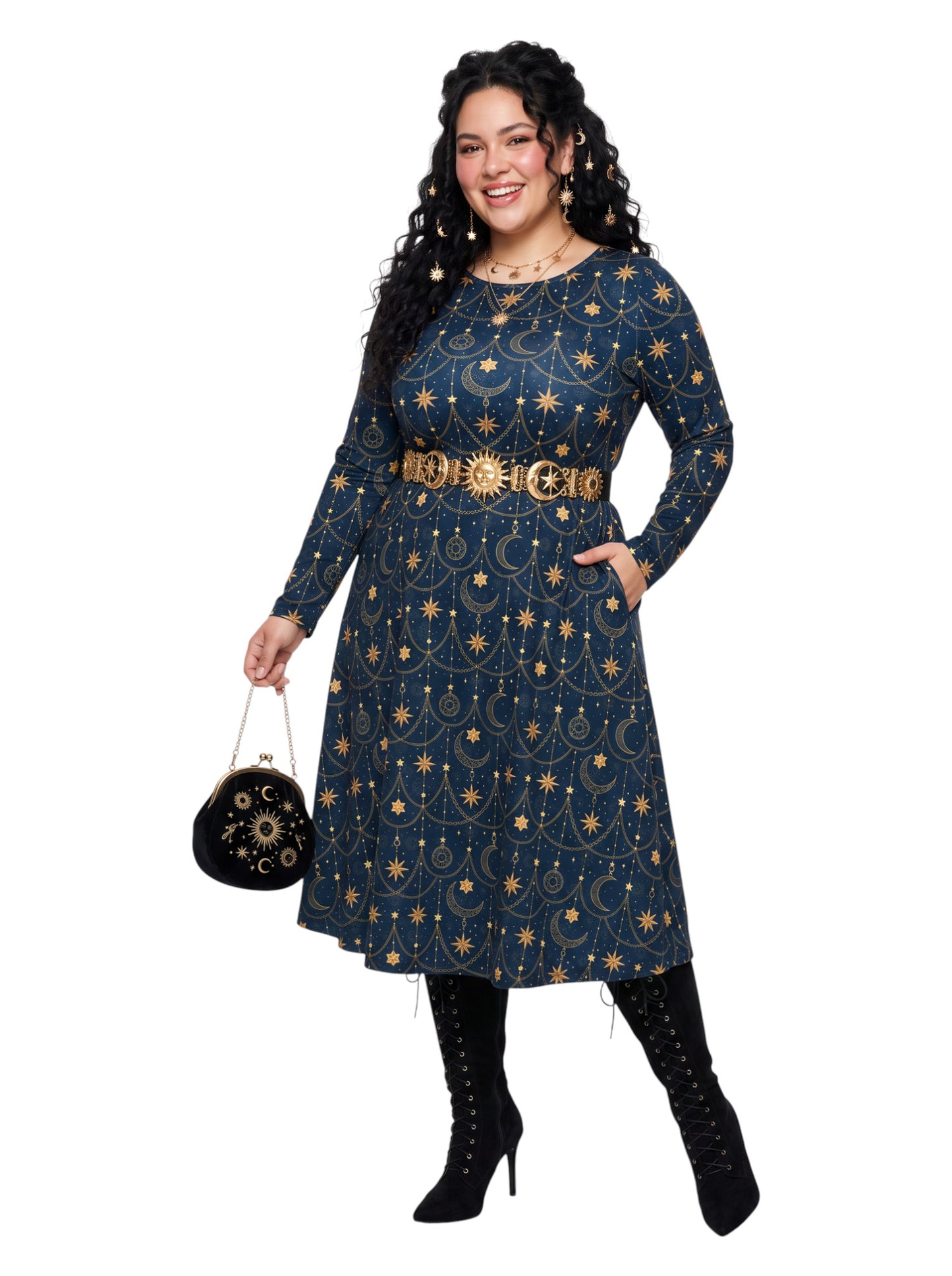 A woman modeling a long-sleeve navy blue dress with a gold celestial print of stars, moons, and ornate line patterns. She is wearing a wide gold belt with a sun design, black lace-up knee-high boots, and holding a small black embroidered clutch bag against a solid white background.