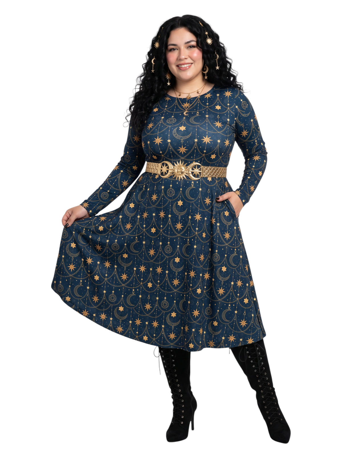 A woman modeling a long-sleeve A-line dress with a celestial print in navy blue and gold, featuring a matching gold belt, black lace-up boots, and gold jewelry against a plain white background.