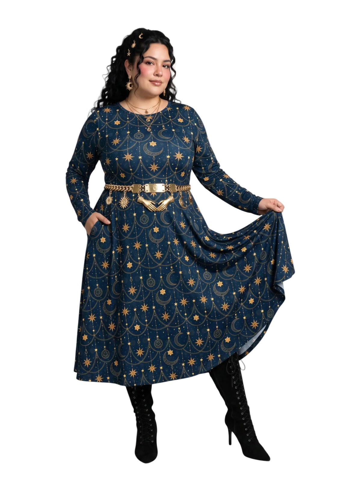 A plus size woman wearing a long-sleeve midi dress with a celestial print in navy blue and gold, featuring a gold chain belt with a decorative buckle, styled with black lace-up boots against a plain white background.