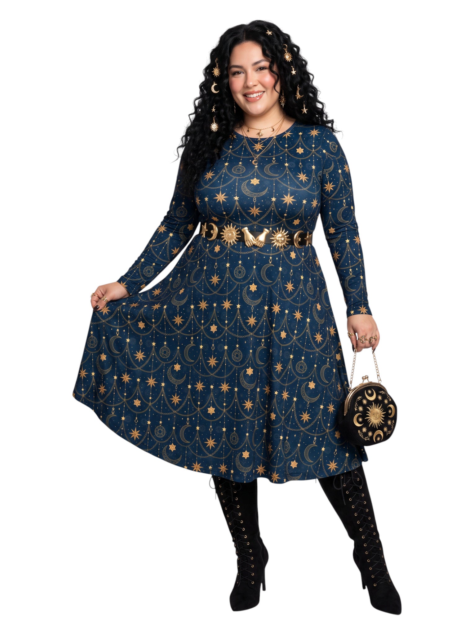 A woman modeling a long-sleeve navy blue dress with a gold celestial print of stars, moons, and suns, styled with a matching belt, black lace-up boots, and a small black and gold handbag against a solid white background.