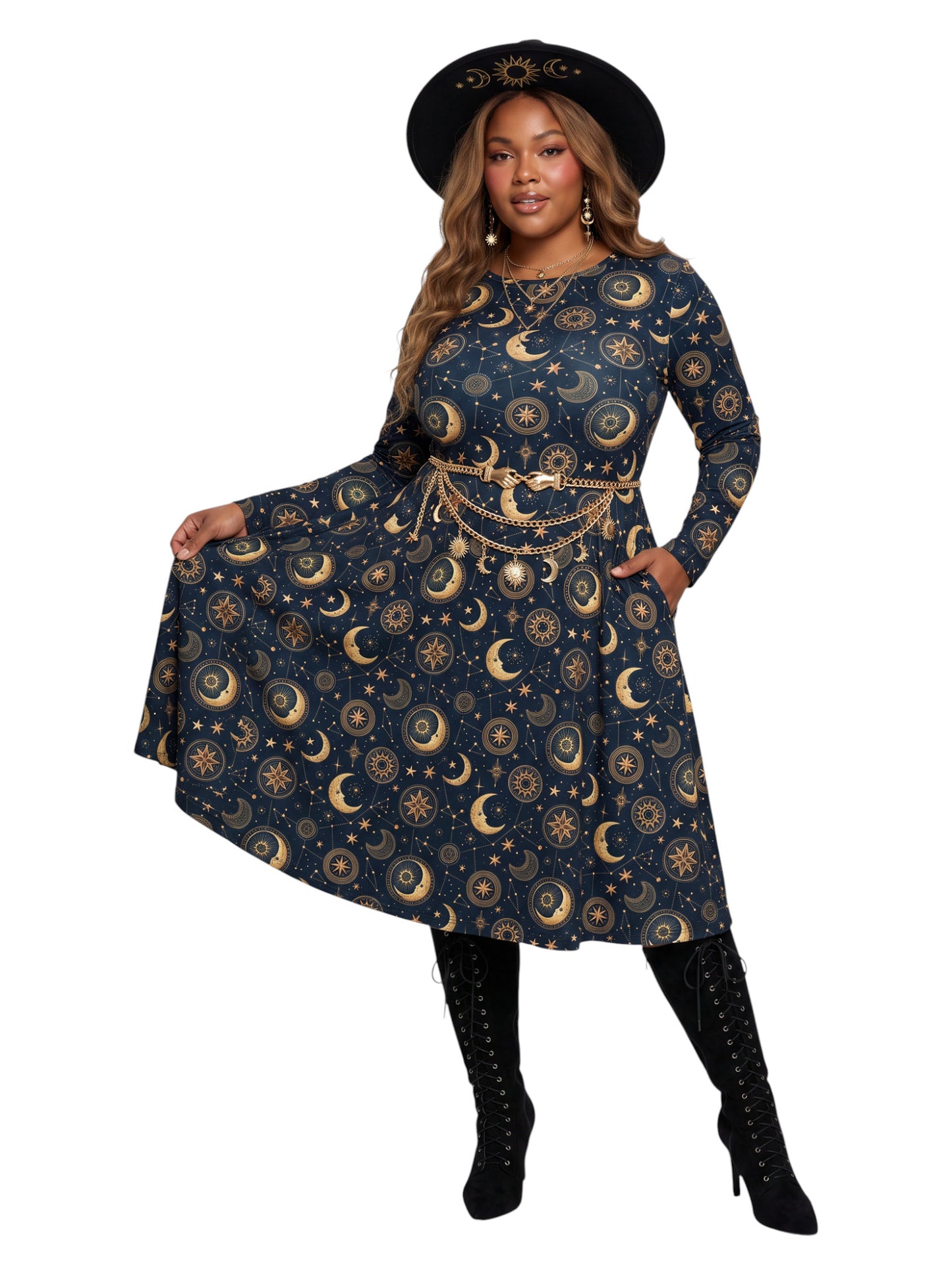 A woman modeling a long-sleeve A-line dress with a celestial print of gold crescent moons and stars on a navy blue background, styled with a gold chain belt, a black hat, and black lace-up boots against a white background.