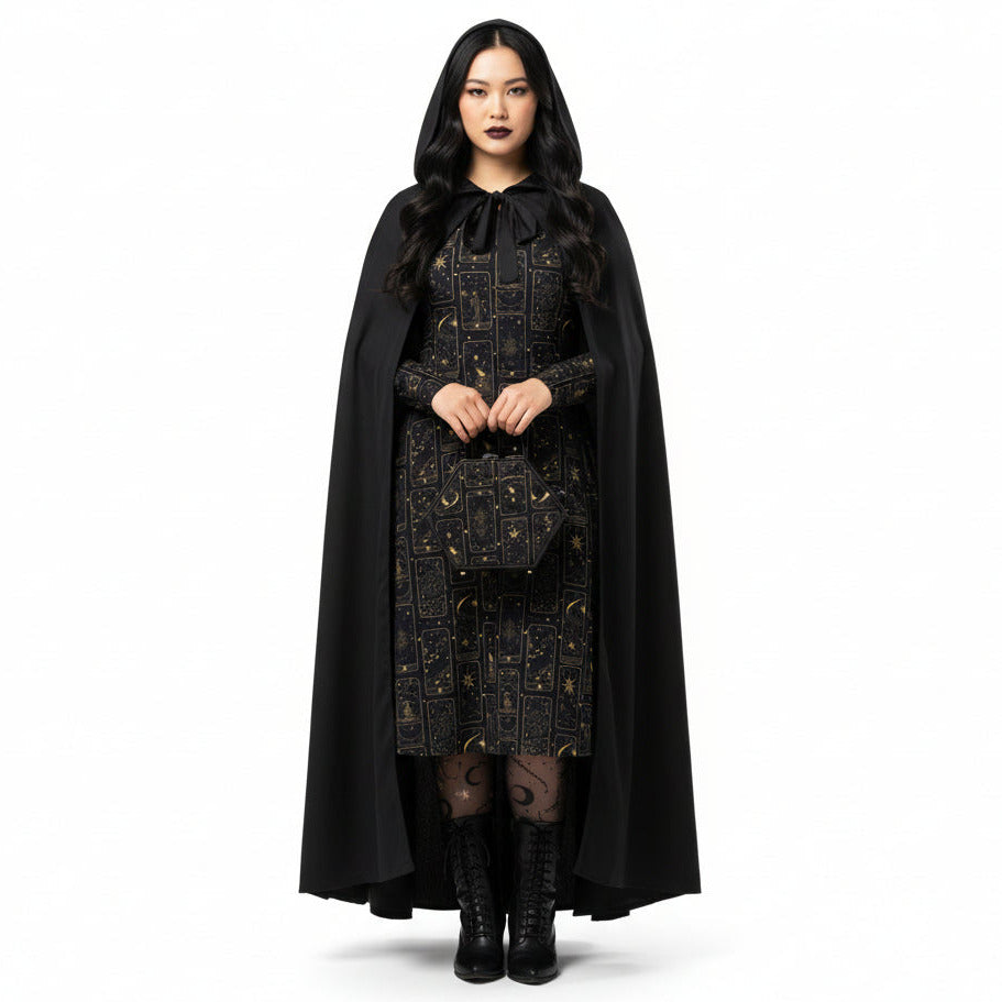 Person wearing a black cape and dress with celestial tarot card print patterns on a white background