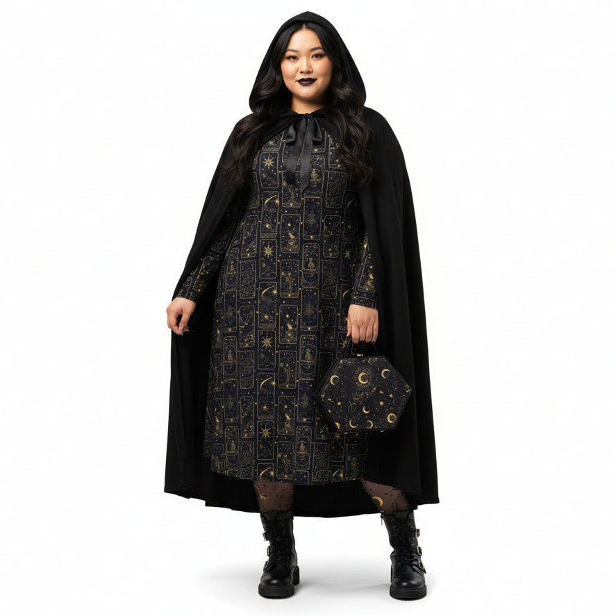Person wearing a celestial tarot card print dress with gold patterns and a matching cape on a white background