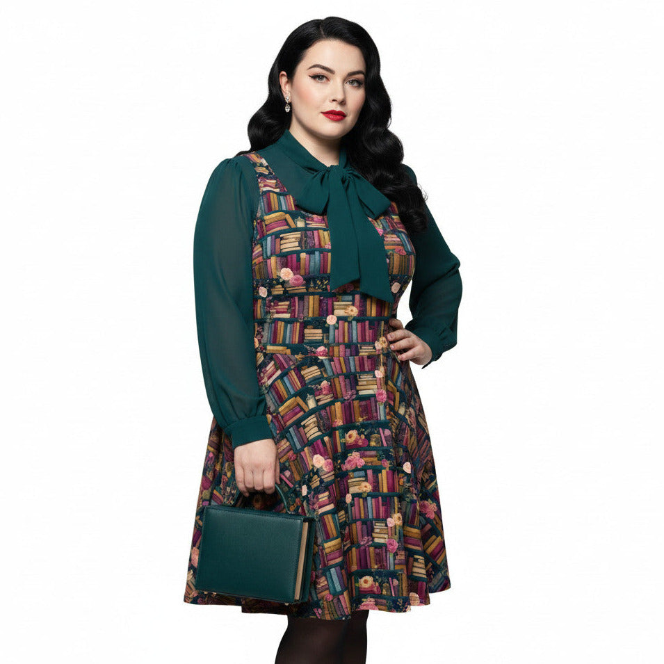 Plus size woman wearing a dark academia bookshelf print skater dress with a green pussy-bow blouse and matching handbag.
