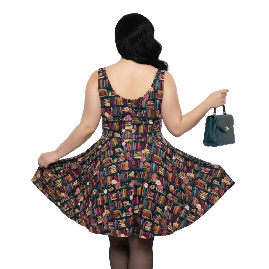 Woman wearing a dark academia bookshelf print skater dress with a teal green handbag.