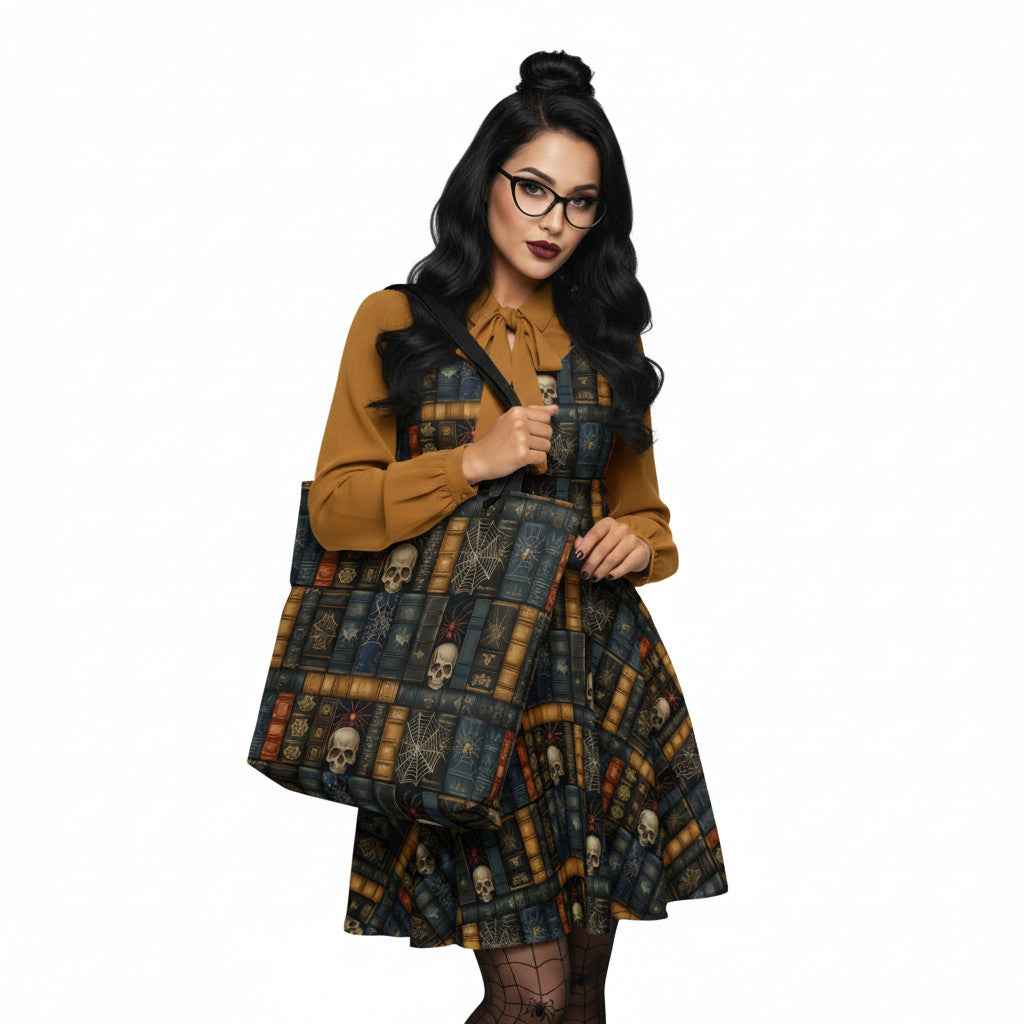 Woman wearing carrying a Dark Academia tote bag with gothic bookshelf print, skulls, and spiderwebs on vintage book spines. The dress matches the tote bag.