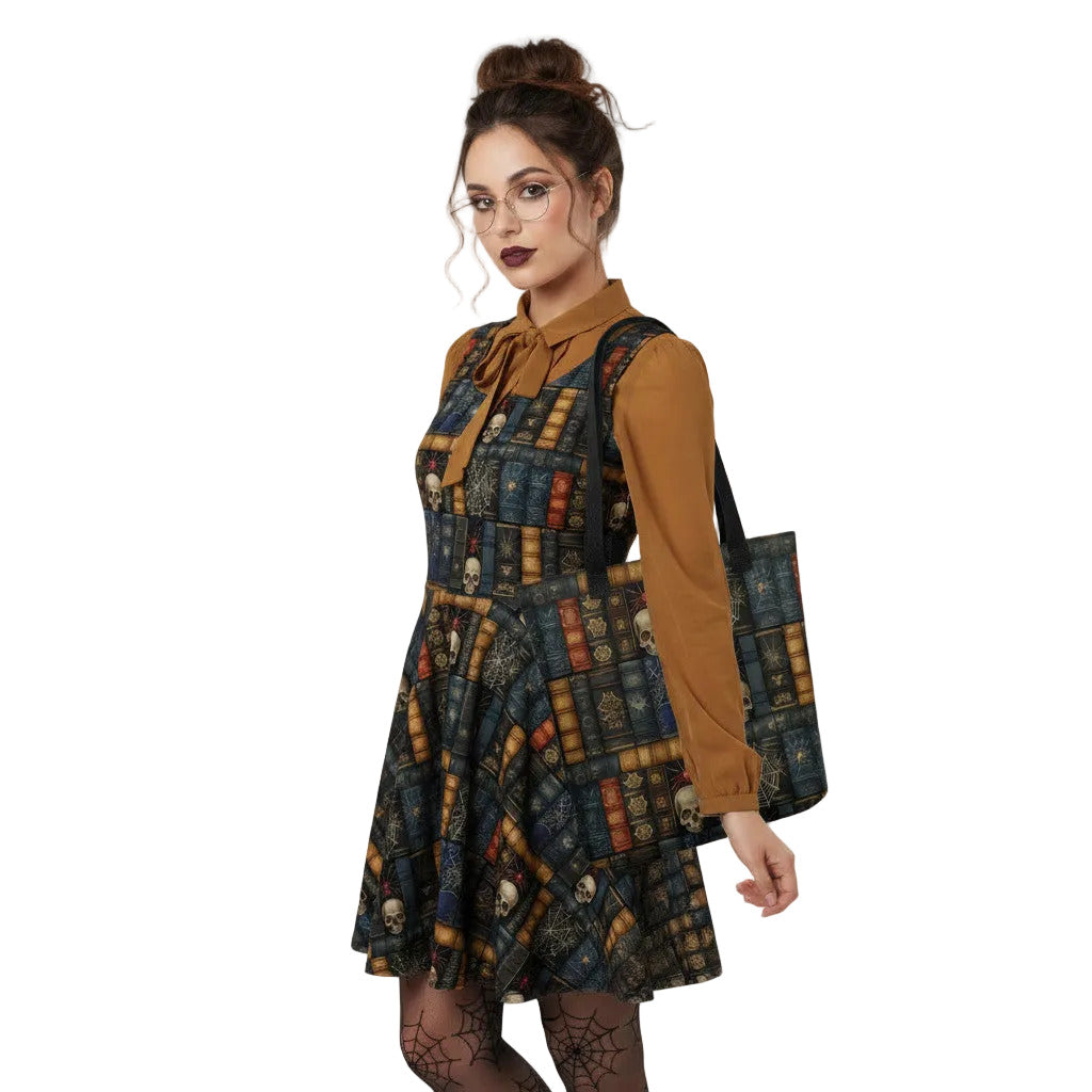 Woman wearing carrying a Dark Academia tote bag with gothic bookshelf print, skulls, and spiderwebs on vintage book spines. The dress matches the tote bag.