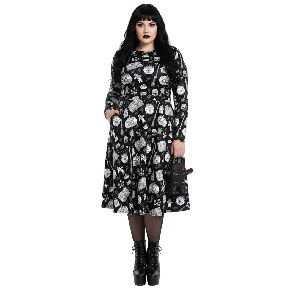 Woman wearing gothic long sleeve midi dress with black and white voodoo doll print and side pockets.