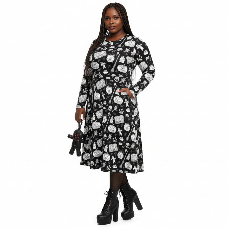 Woman wearing gothic long sleeve midi dress with black and white voodoo doll print and side pockets.