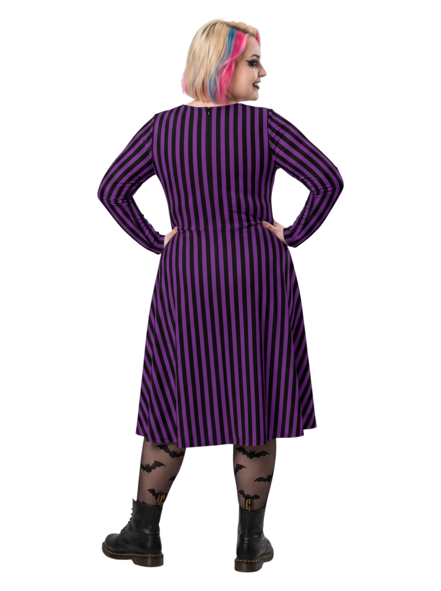 Plus size woman modeling gothic purple and black vertically striped long sleeve fit and flare midi dress with side pockets