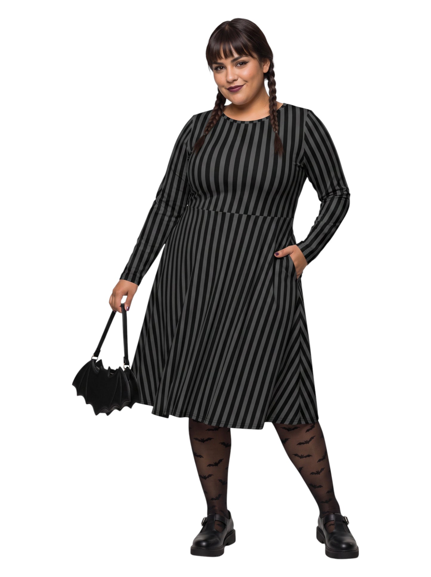 Plus size woman wearing a gothic grey and black vertically striped fit and flare midi dress with long sleeves, functional side pockets, and a scoop neckline.
