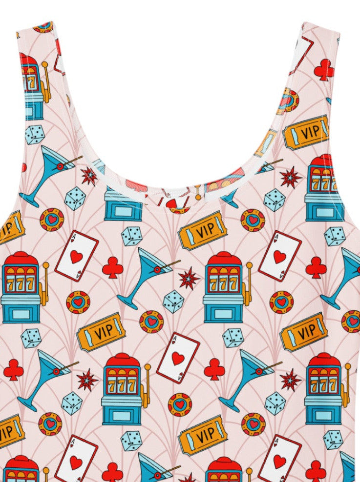A sleeveless white pinup swing dress with a colorful retro-themed print featuring playing cards, slot machines, and dice, shown flat against a white background.