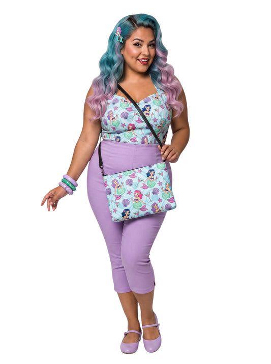 A woman wears as mermaids, martinis and seashells convertible clutch and crossbody bag in faux leather with adjustable strap.