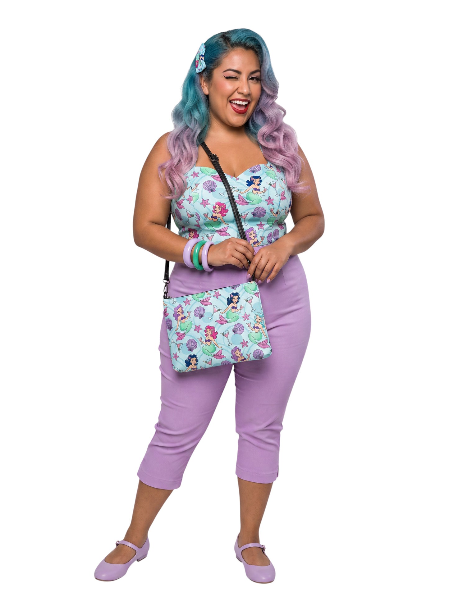 A woman wears as mermaids, martinis and seashells convertible clutch and crossbody bag in faux leather with adjustable strap.