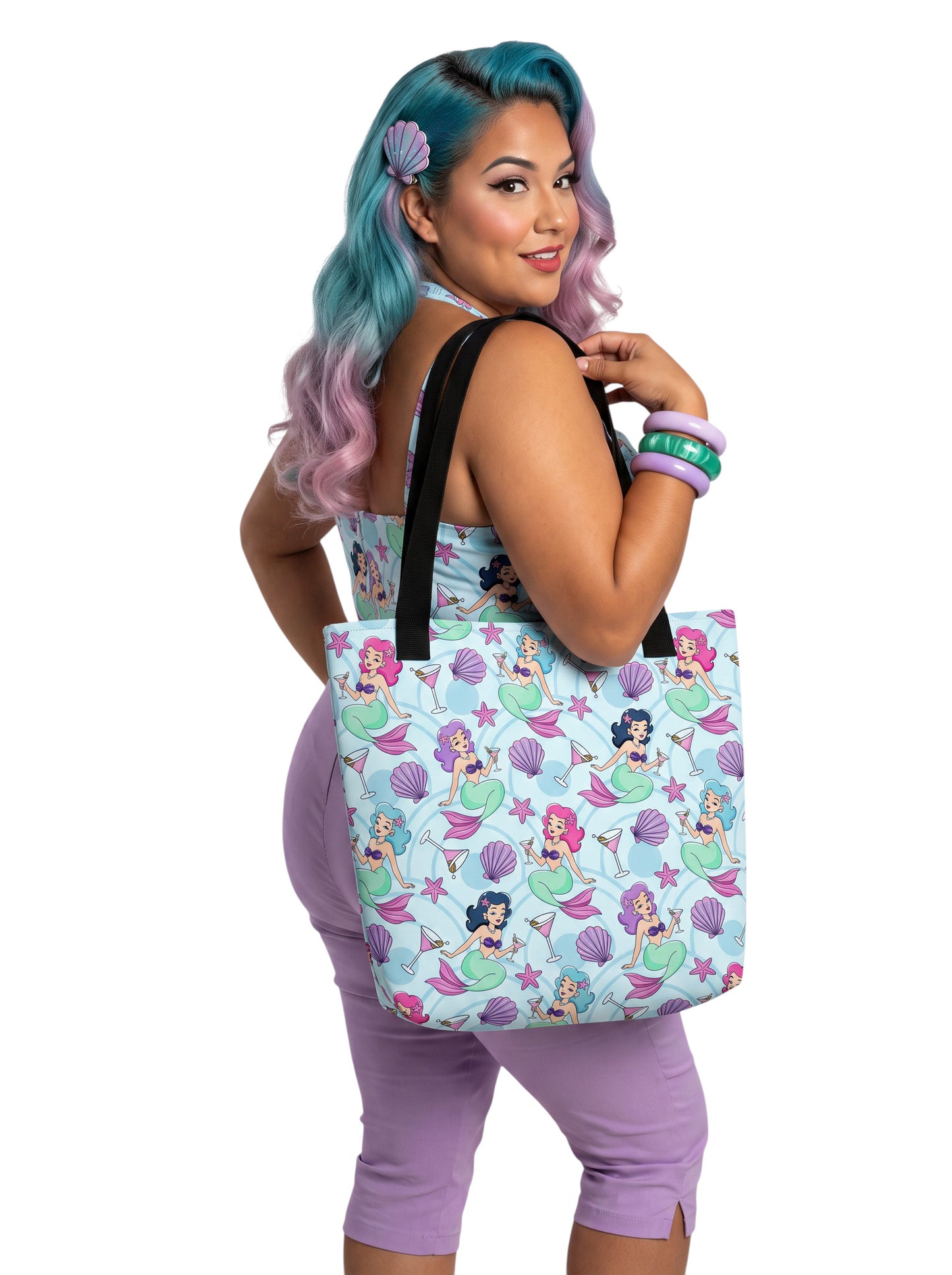 A pinup girl woman wearing a matching mermaid and martini print beach tote bag, lavender purple pinup top and capri pants.