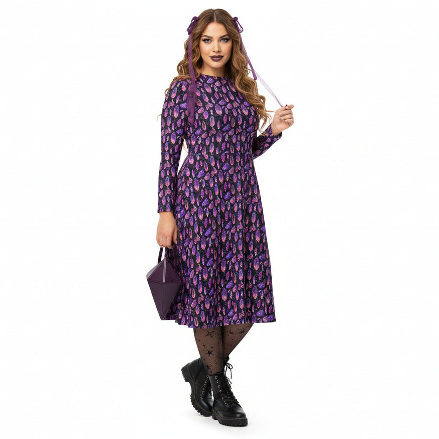 Woman wearing a purple crystal print  dress holding a wand on a white background