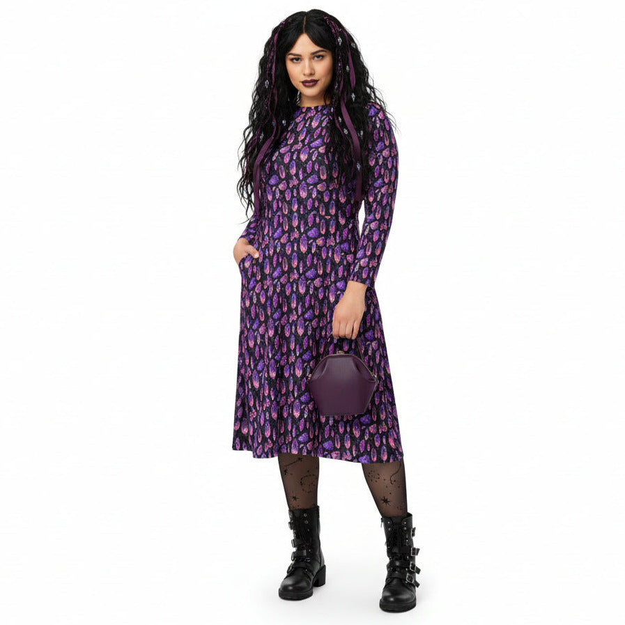 Person wearing a purple crystal print dress with a matching handbag on a white background