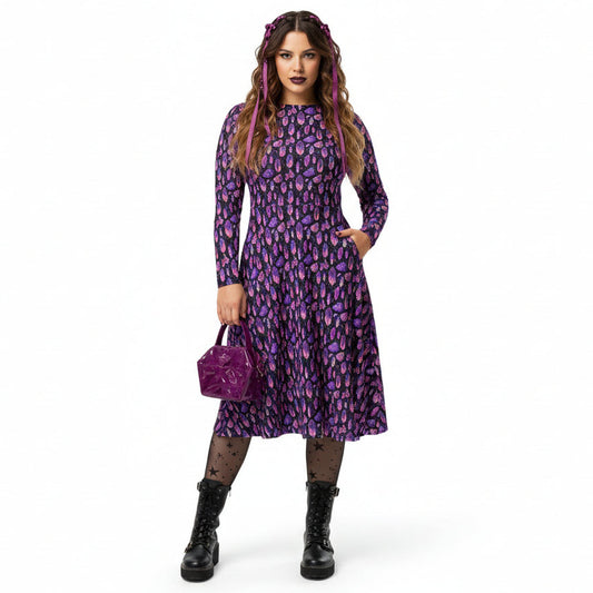 Woman wearing a purple crystal print  dress holding a matching handbag on a white background