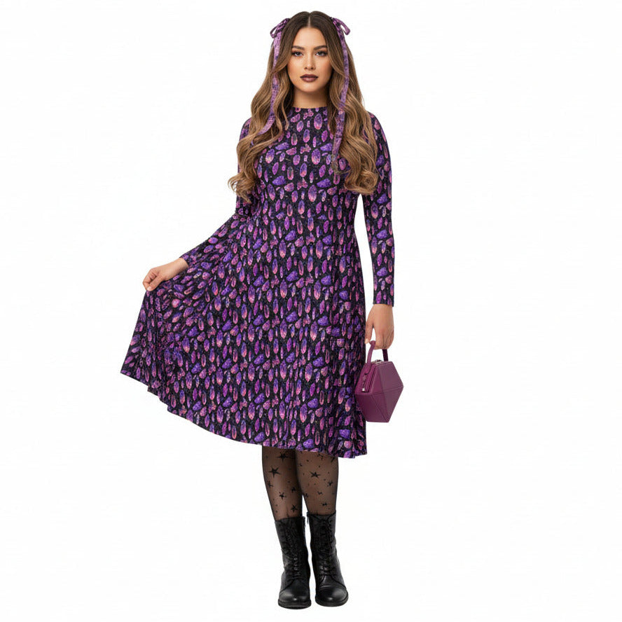 Woman wearing a purple crystal print  dress with a matching handbag on a white background