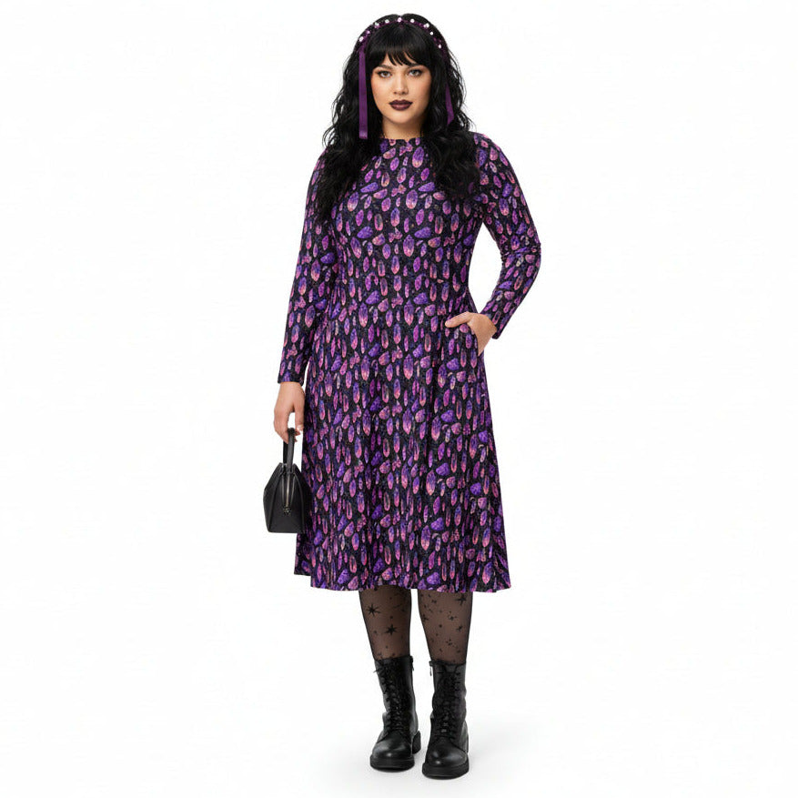 Woman wearing a purple mystical crystal print dress with a floral pattern on a white background