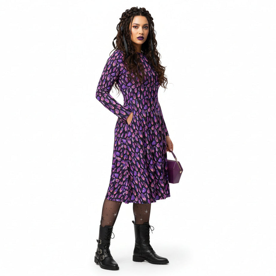 Woman wearing a purple floral dress with black boots on a white background