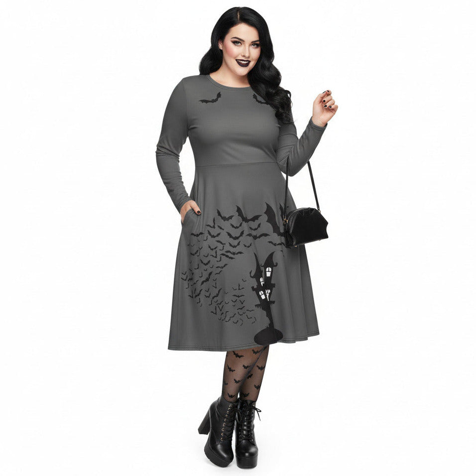 Plus size woman wearing a grey long sleeve goth pinup dress with black bat and haunted house print featuring functional side pockets.
