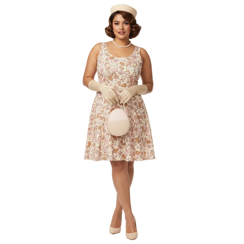 Plus size woman wearing a 1950s vintage style swing dress with pink and tan Easter egg and bunny print, featuring a sleeveless scoop neck and flared skirt.