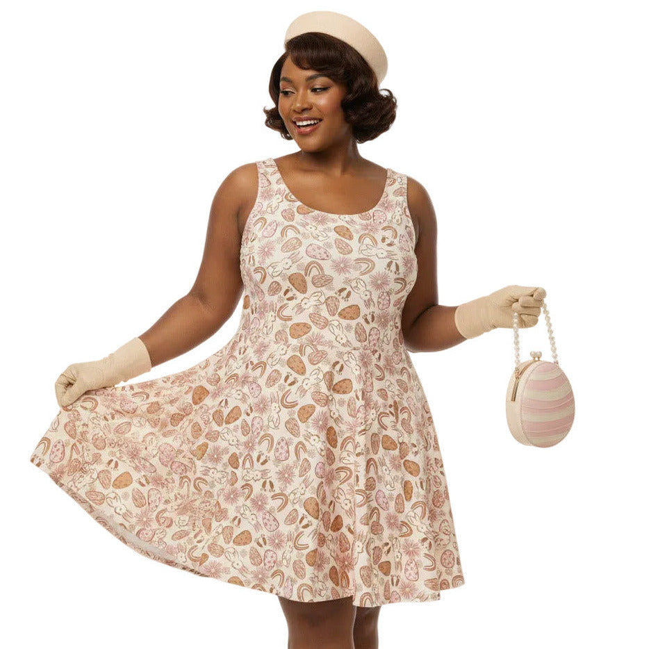 Plus size woman wearing a 1950s vintage style swing dress with pink and tan Easter egg and bunny print, featuring a sleeveless scoop neck and flared skirt.