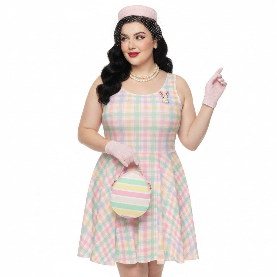 Plus size woman wearing a pastel pink and green gingham 1950s vintage style swing dress with matching pillbox hat and gloves.
