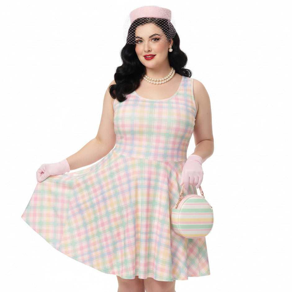 Plus size woman wearing a pastel pink and green gingham 1950s vintage style swing dress with matching pillbox hat and gloves.