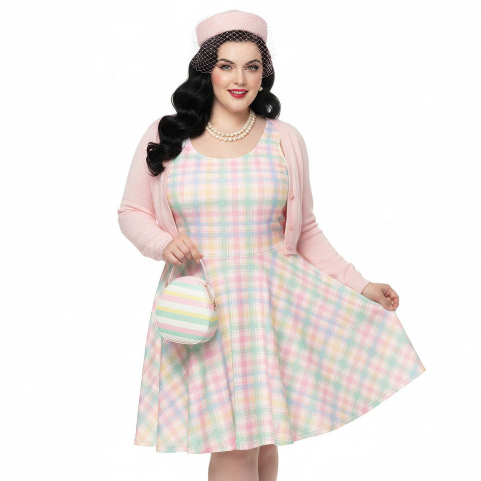 Plus size woman wearing a pastel pink and green gingham 1950s vintage style swing dress with matching pillbox hat.