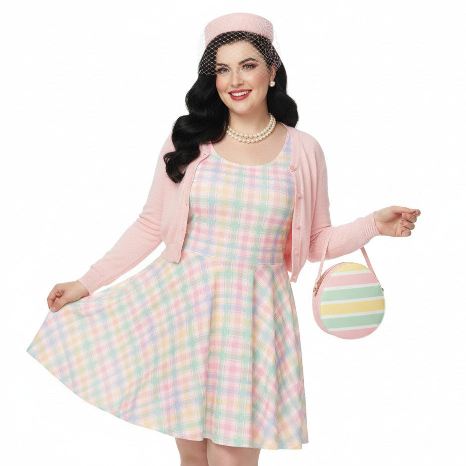 Plus size woman wearing a pastel pink and green gingham 1950s vintage style swing dress with matching pillbox hat.