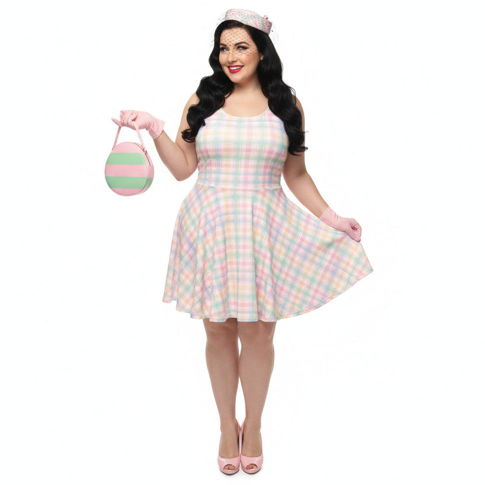 Plus size woman wearing a pastel pink and green gingham 1950s vintage style swing dress with matching pillbox hat and gloves.