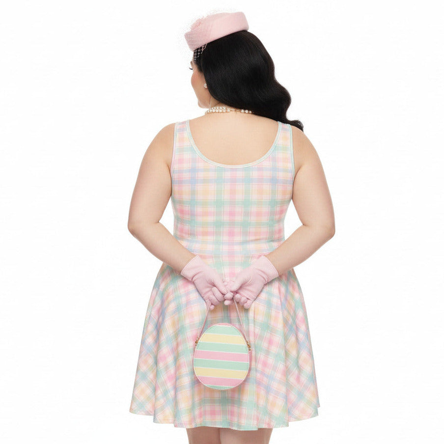 Plus size woman wearing a pastel pink and green gingham 1950s vintage style swing dress with matching pillbox hat and gloves.